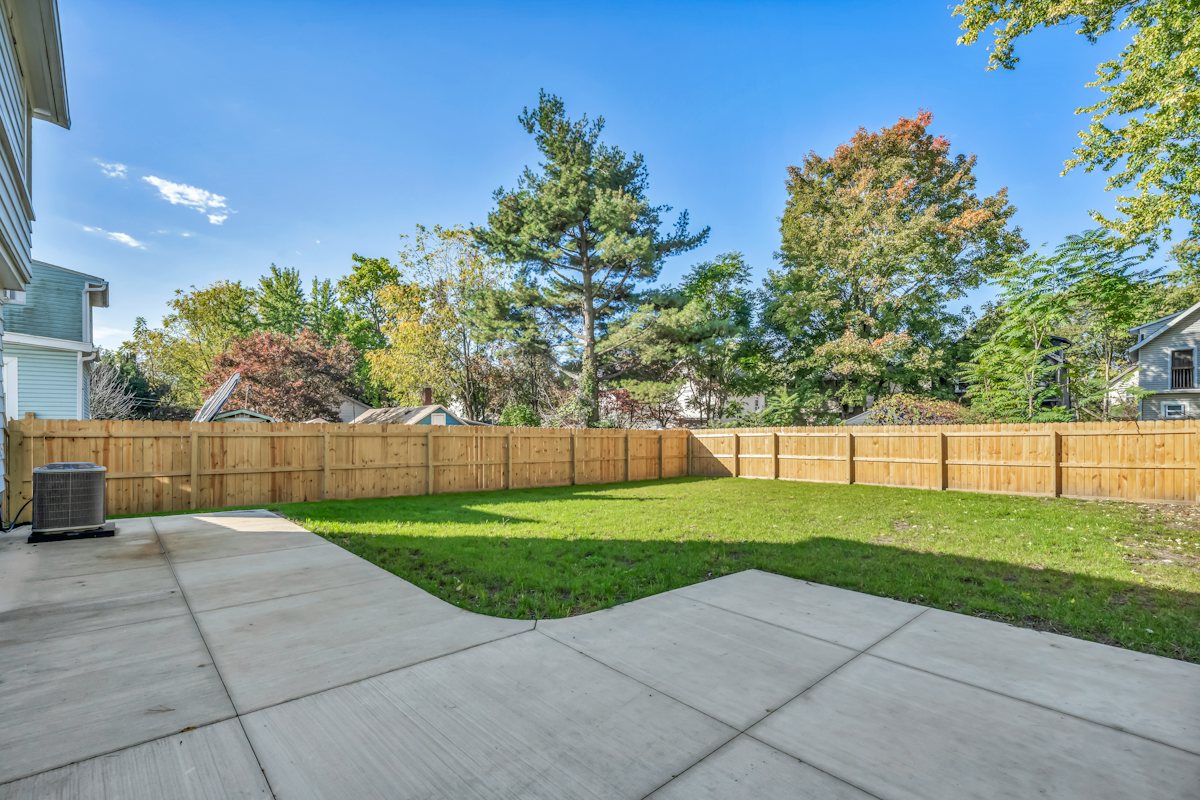 Concrete patio beside a green lawn inside a wooden privacy fence