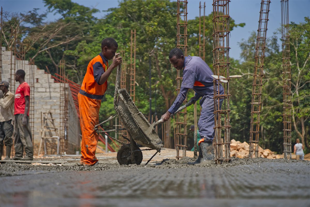 Crew pouring a concrete floor slab with a wheelbarrow